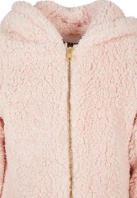 Rosa, fluffy zip-jakke med hette, med en hel-lengde gullglidelås. Stoffet har en teksturert, teddy-bear-lignende utseende.