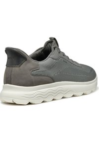 Sneaker grigia con tomaia in mesh, dettagli in suede, colletto imbottito e suola bianca testurizzata con motivo a onde. Visibile il marchio Geox.