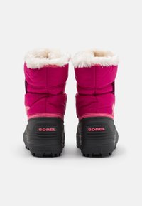 Stivali isolati rosa con bordo in finta pelliccia, suole in gomma nera e logo Sorel sul retro. Presentano un design trapuntato per una maggiore texture.