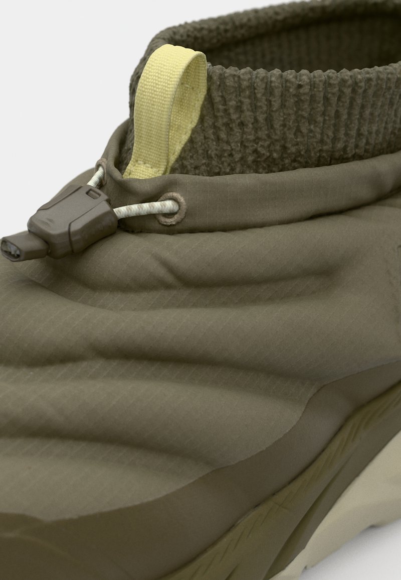 Groene, gevoerde schoen met een gestructureerde bovenkant, elastische kraag en gele treklus. Voorzien van een toggelsluiting en rubberen zool.