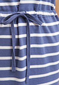 Robe en coton avec un motif rayé bleu marine et blanc. Elle possède une taille à cordon et une texture douce.