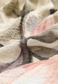 Abstraktes gemustertes Gewebe in sanften Pastellfarben wie Rosa und Beige, mit einer strukturierten Webart und einem glatten, fließenden Design.