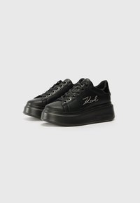 Baskets à plateforme noires avec une finition en cuir lisse, design à lacets, œillets en métal argenté et logo brodé sur le côté. Semelle texturée.