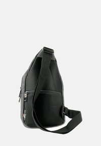 Zwarte schoudertas gemaakt van gestructureerde stof met geperforeerd ontwerp, voorzien van een hoofdcompartiment, verstelbare schouderband en ritssluitingen.