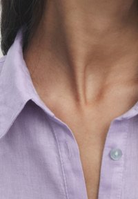 Lavender, button-up shirt with a structured collar and a glossy, light blue button, featuring a soft, textured fabric.