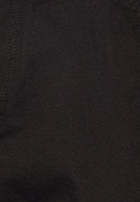 Černá denimo tkanina s hladkou strukturou a diagonálním vzorem. Obsahuje pevný šev a jemné variace v odstínu.