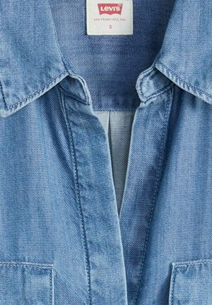 Cuello y área del pecho de chaqueta de mezclilla azul claro con etiqueta Levi's que muestra la talla Pequeña y la ubicación de San Francisco, California.