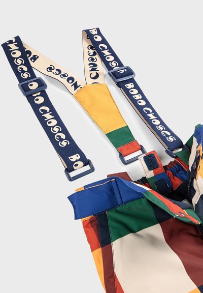 Mønstret suspender shorts i mange farver med et patchwork-design, der har marineblå stropper med 'BOBO CHOSES' branding og flerfarvede accenter på stoffet.