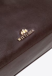 Bruine leren handtas met een gestructureerde afwerking, gouden hardware en een prominent Wittchen-logo aan de voorkant.