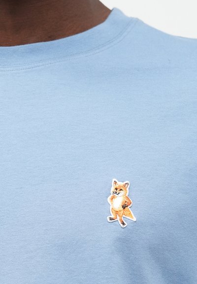 Ανοιχτό μπλε βαμβακερό T-shirt με μια μικρή κεντημένη απεικόνιση αλεπούς στο αριστερό στήθος, με πορτοκαλί και λευκές λεπτομέρειε�ς.