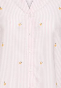 Chemise à rayures verticales rose clair et blanc avec de petits motifs de fruits orange et des boutons blancs au centre devant.