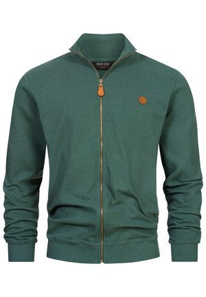 Green zip-up sweatshirt with ribbed texture, high collar, and leather zip pull. Features a small logo patch on the chest.