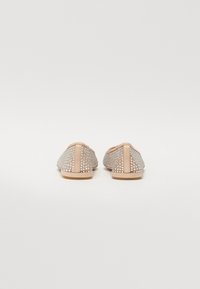 Scarpe open-back con una base in pelle nude e dettagli in strass argentati. Presentano una texture liscia e una suola piatta.