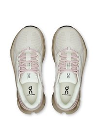 Beige és fehér futócipők egy pár rózsaszín fűzővel, hálós anyagú felsőrésszel és "Cloudrunner" márkázással a talpban, felülről nézve.