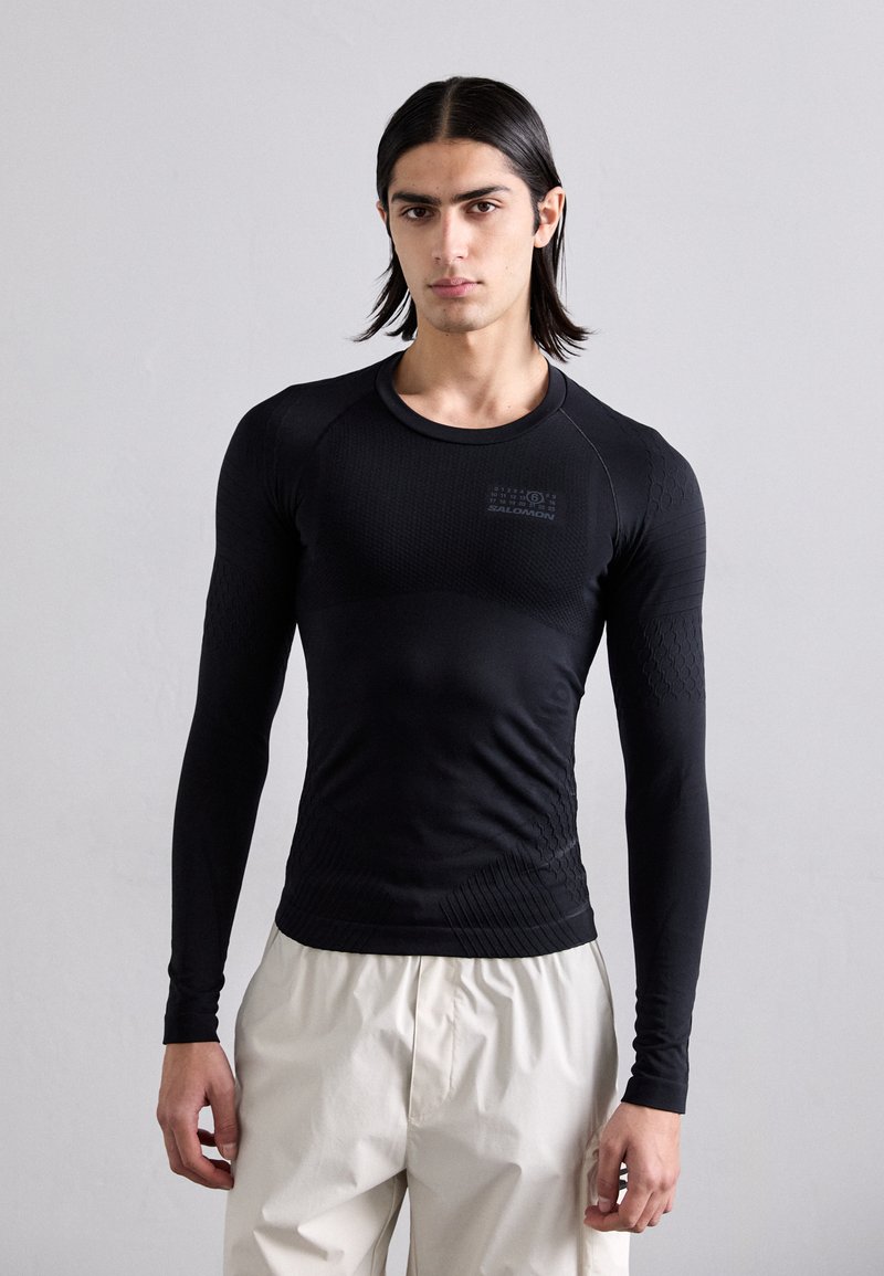 Camisa de mangas longas ajustada em preto, com padrões texturizados e tecido em malha para respirabilidade. Decote arredondado e design elegante.