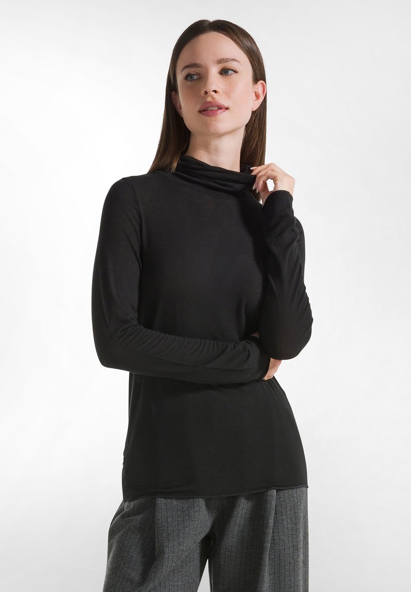 Maglia nera a maniche lunghe con collo alto in materiale morbido e elastico, dal taglio rilassato, con scollo drappeggiato e maniche aderenti.