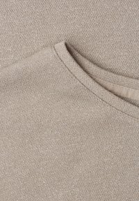 Close-up of beige knitted fabric with subtle metallic threads and a rounded neckline with visible stitching detail.