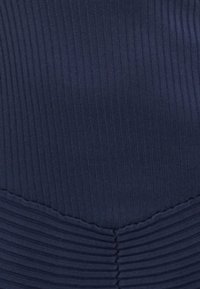Tejido de ribetes en color navy con líneas verticales. Presenta una textura fruncida en la parte inferior, creando un patrón horizontal distintivo. Acabado suave y liso.