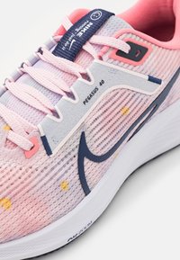 Zapatillas Nike Pegasus 40 con parte superior de malla en rosa claro y lavanda, con detalles en azul, patrones texturizados y una suela blanca.