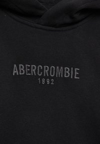 Zwarte capuchontrui met de woorden "ABERCROMBIE" en "1892" in het grijs geborduurd op de voorkant. Zachte textuur, minimalistisch ontwerp.