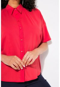 Camicia rossa con bottoni, maniche corte, texture liscia e colletto classico. Presenta bottoni abbinati lungo la parte anteriore.