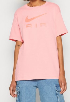 T-shirt en coton rose à manches courtes avec un col rond. Présente un logo Nike délavé et un graphique "AIR" de la même couleur.