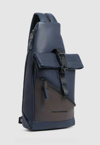 Borsa a tracolla in pelle blu navy con patta testurizzata, tasca laterale con zip e dettagli marrone scuro. Dotata di tracolla regolabile e dettaglio con logo.