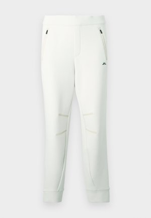 Biele tepláky z mäkkej tkaniny, s dvoma vreckami na zips, akcentovanými švami a rebrovanými manžetami pre priliehavejší vzhľad.