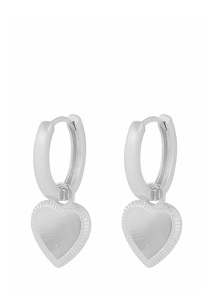 Silver hoop earrings with small heart-shaped charms featuring a ridged border detail on a white background.