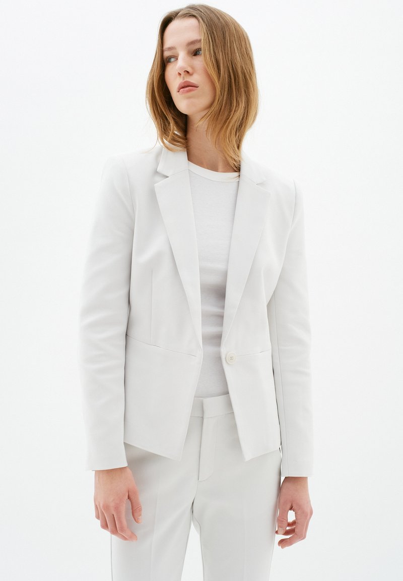 Lichtgrijze blazer in een getailleerd ontwerp, met een enkele knoopsluiting, notch-revers en twee voorkwaliteiten. Matte textuur.