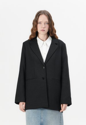 Blazer noir au design ajusté, présentant des revers à notches, une fermeture à un bouton et deux poches avant. Texture lisse avec un minimum de détails.