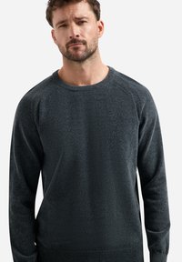 Donkergrijze sweater met ronde hals, gemaakt van gestructureerde brei-stof. Kenmerkt zich door ribbelstructuur op de mouwen en onderkant, met een ontspannen pasvorm en lange mouwen.