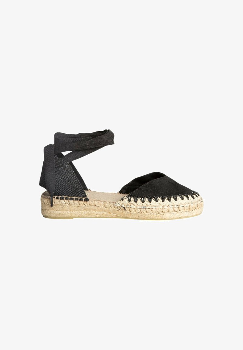 Espadrille negra con suela de yute trenzado, tejido que envuelve el talón y correas cruzadas para atar. Presenta un perfil plano y un diseño de punta afilada.