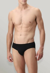 Completo intimo nero caratterizzato da un tessuto liscio, design a vita bassa e una cintura elastica minimalista. Senza motivi o accenti aggiuntivi.