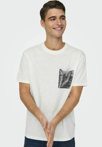 T-shirt bianca a maniche corte con taschino sul petto grigio a motivo. Realizzata in tessuto morbido, presenta un collo rotondo e una vestibilità comoda.