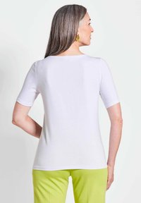 Witte top met korte mouwen, een ronde halslijn, een strakke pasvorm en een gladde stof, gecombineerd met felgroene broek.