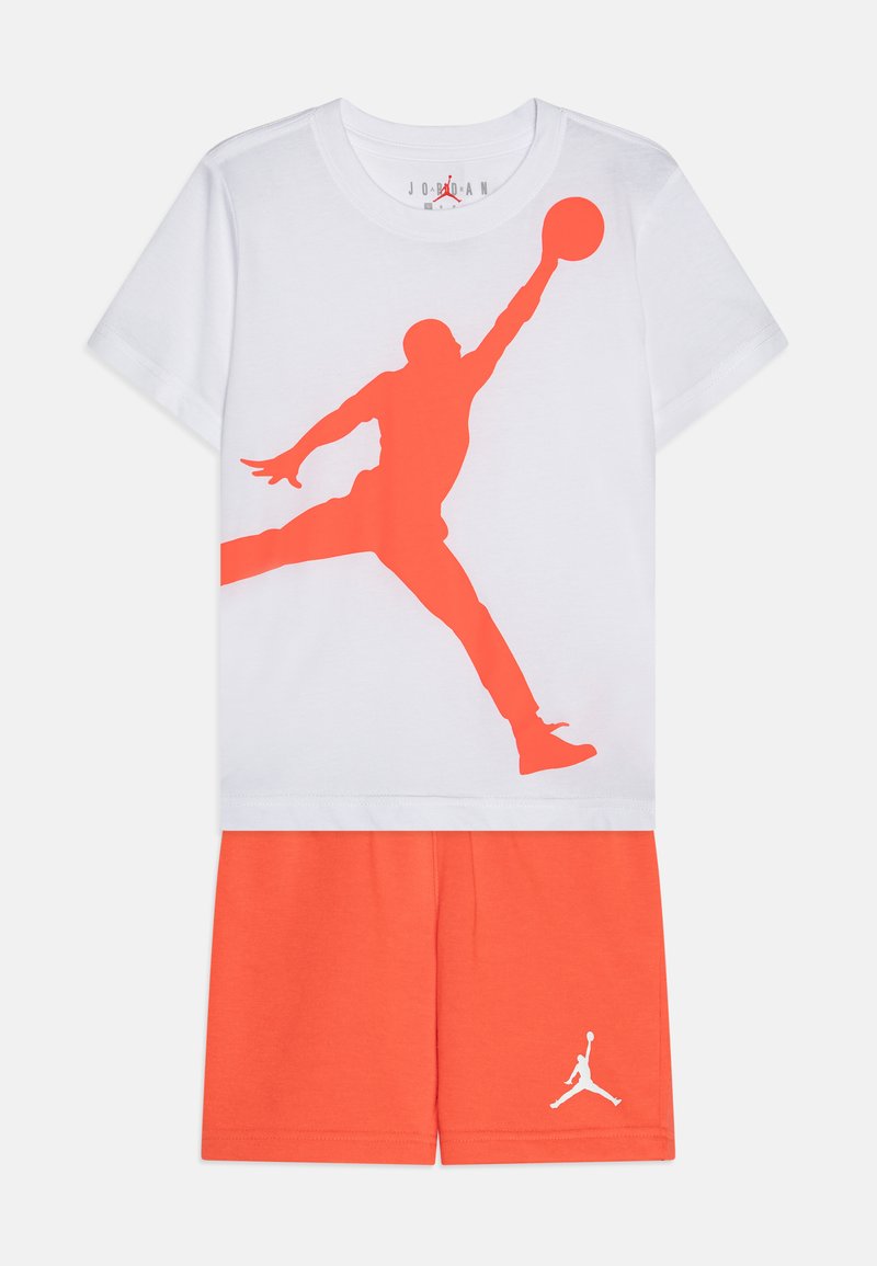 Λευκό T-shirt με μια μεγάλη πορτοκαλί σιλουέτα γραφικού ενός παίκτη μπάσκετ. Συνδυάζεται με πορτοκαλί σορτς που διαθέτουν λευκή λογότυπη λεπτομέρεια.