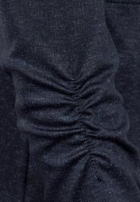 Tissu bleu foncé avec une texture légèrement chinée. Présente un détail froncé le long de la manche pour plus de dimension.