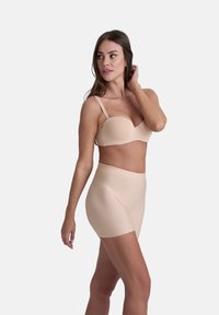 Nude sömlös bh med en konturerad form och justerbara axelband, tillsammans med högmidjad nude formande shorts i ett mjukt, elastiskt material.