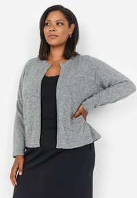 Grå stickad cardigan med rund halsringning, långa ärmar och fickor; bärs över en svart topp med en strukturerad yta.