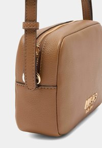 Brun læder crossbody taske med guldtonet hardware, rektangulær form, tekstureret overflade og lynlåslukning. Brandlogo prægede på siden.