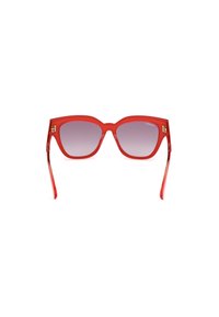 Gafas de sol rojas de plástico translúcido con una forma geométrica sobredimensionada. Lentes ahumadas con degradado y detalles metálicos en las patillas.