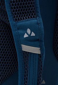 Tessuto blu con texture a rete, caratterizzato da un logo grigio chiaro e dettagli in accentuazione argento, che evidenziano diversi materiali e finiture.