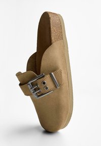 Ruske nubukklumper med bred såle, justerbar metalspænde, kork-mellemsål og struktureret gummisål. Stilet minimalistisk design.