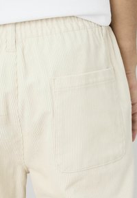 Pantalons en velours côtelé de couleur crème avec une texture côtelée, dotés d'une taille élastique et d'une poche arrière plaquée.