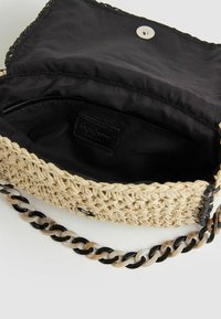 Piccola borsa a tracolla beige intrecciata con interno in tessuto nero e tracolla in catena marmorizzata nera, bianca e marrone, con pattina aperta e chiusura a pressione magnetica.