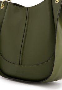 Olijfgroene leren handtas met een gladde afwerking, gebogen vorm, contrasterende zwarte stiksels en gouden hardwareaccenten. Logo is op de voorkant gebosseld.
