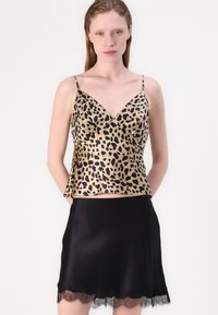 Leopardmönstrad satinlinne med tunna axelband, i kombination med en svart satin kjol med spetskant. Slät textur, figurnära design.