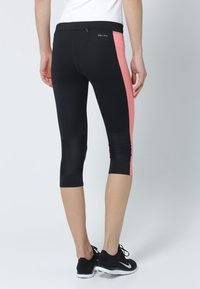 Black Dri-FIT capri leggings with a pink side panel, featuring a smooth texture, elastic waistband, and fitted design.