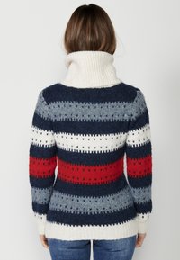 Pull en tricot avec un col montant, orné de rayures horizontales bleu marine, gris, rouge et blanc, texturé avec de petits motifs découpés.
